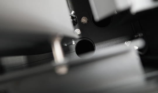 Pogled od blizu na notranji del pergole z vidnim integriranim sistemom za odvodnjavanje, ki prikazuje cev in vijake konstrukcije.